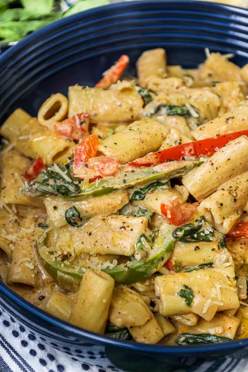 Rasta pasta in a blue bowl topped with fresh cracked peppers