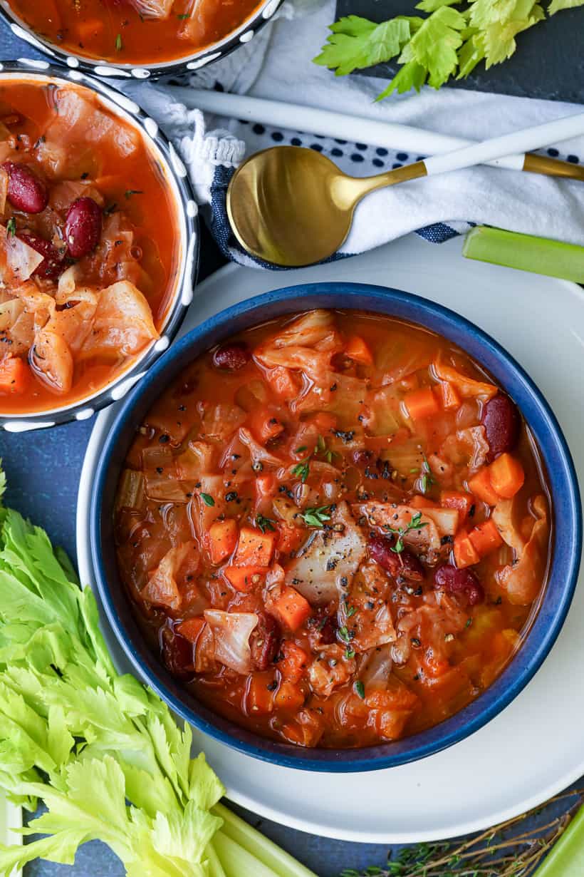 Instant Pot Cabbage recipe in a blue bowl topped with fresh herbs and olive oil.