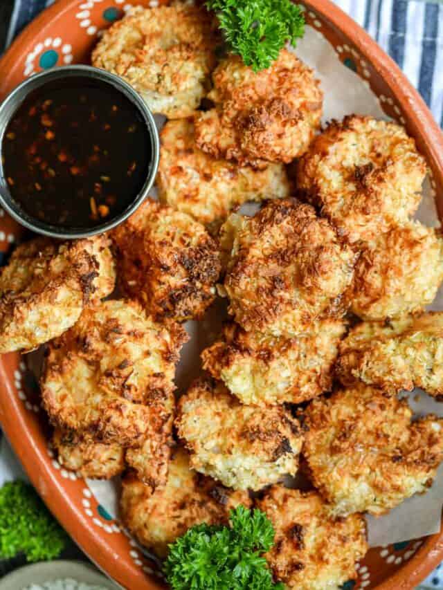 Crunchy coconut shrimp topped with fresh parsley and sauce on a brown plate