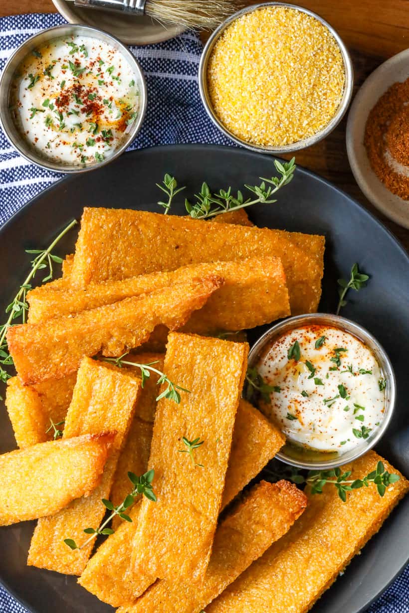 Polenta fries on black tray with fresh herbs