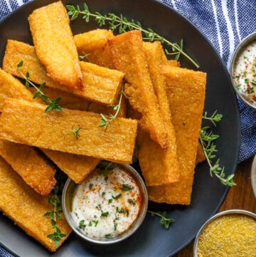 Polenta fries on black tray with fresh herbs