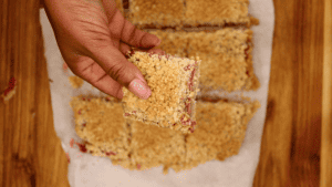 hands holding Raspberry Bars with oatmeal crumble.