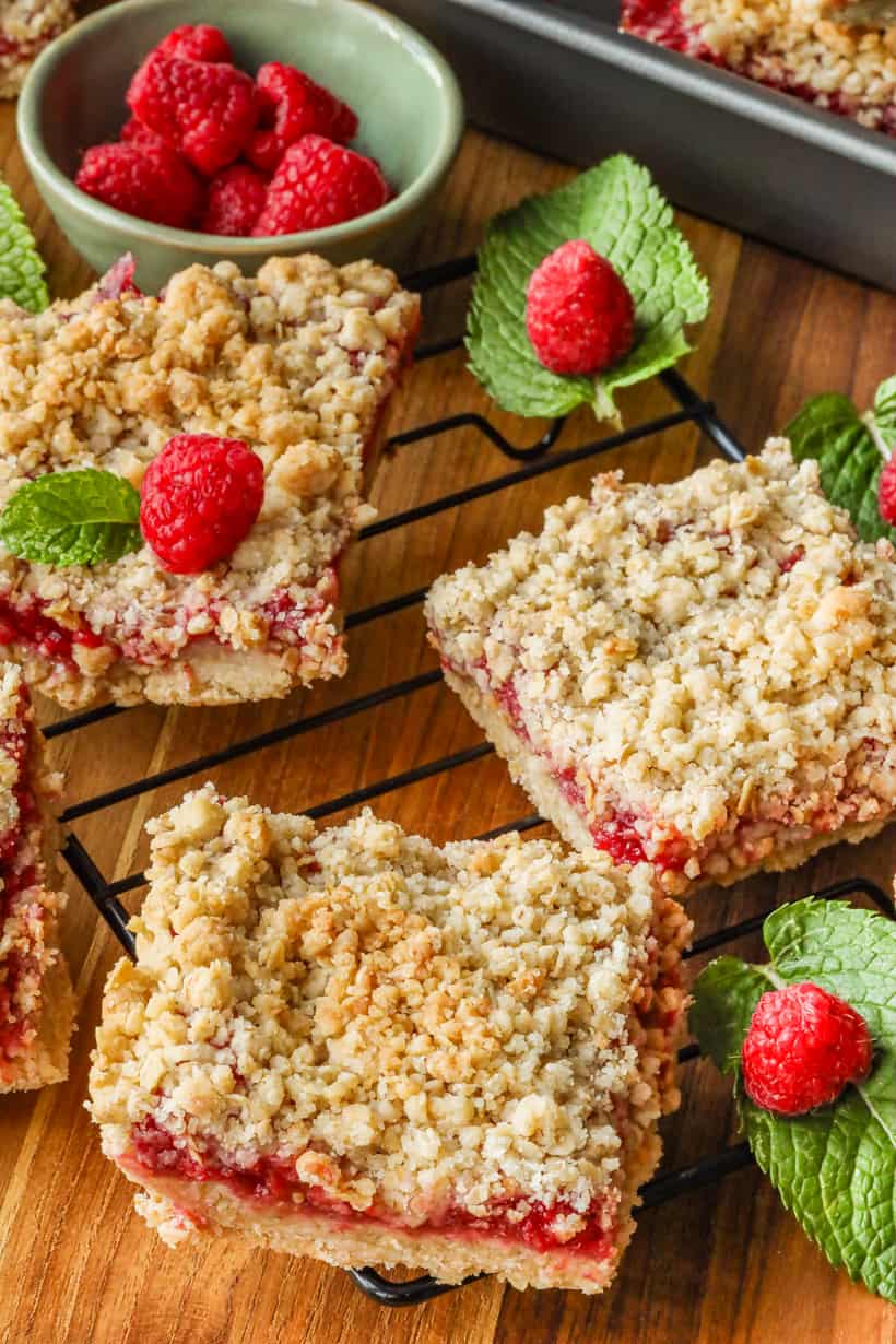 Raspberry Bars on a cooling rack and mint topped with fresh raspberries.