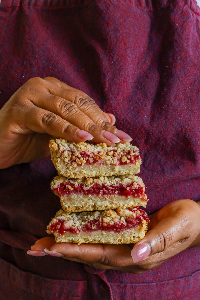 hands holding Raspberry Bars with oatmeal crumble.