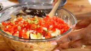 adding fresh veggies to potatoes and eggs