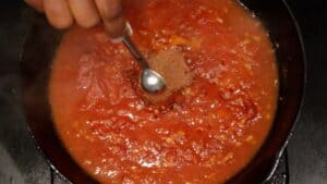 Adding Jacmel seasoning to tomato mixture