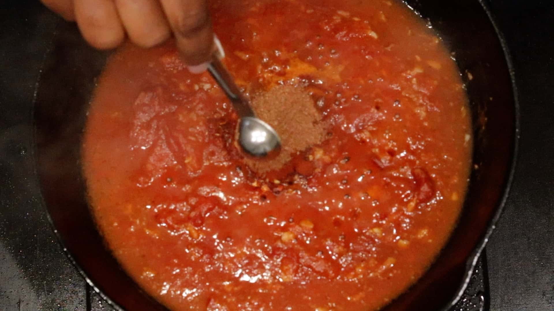 Adding Jacmel seasoning to tomato mixture