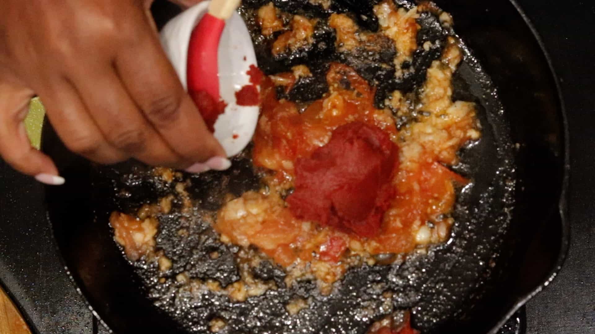 adding tomato paste to tomatoes.