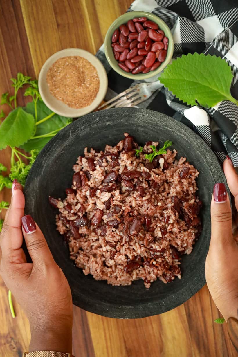 Hands holding Bowl filled with red beans and rice.