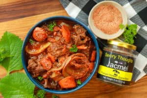 Haitian short ribs stew in blue bowl with rice and Jacmel seasoning blend.