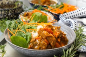 Curry goat in bowl with rice and vegetables