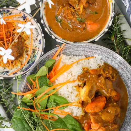 Cooked Curry Goat recipe in bowl with greens and rice