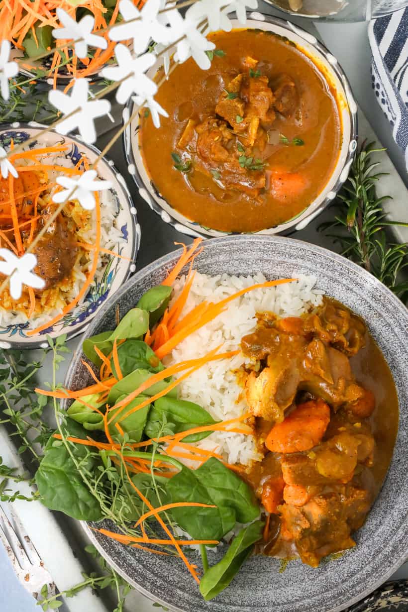 Cooked Curry Goat recipe in bowl with greens and rice