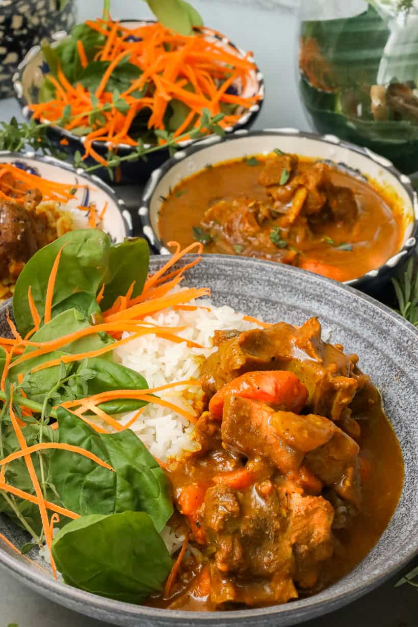 Curry Goat in bowl with rice and spinach