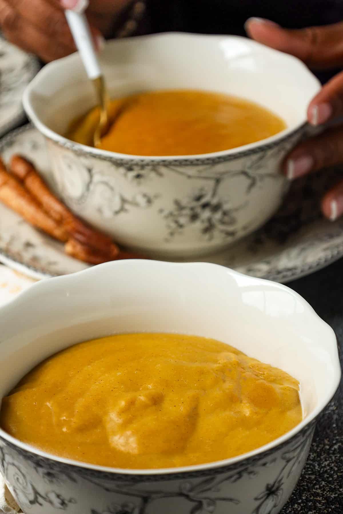 Plantain porridge in bowl with hand holding the back of the bowl.