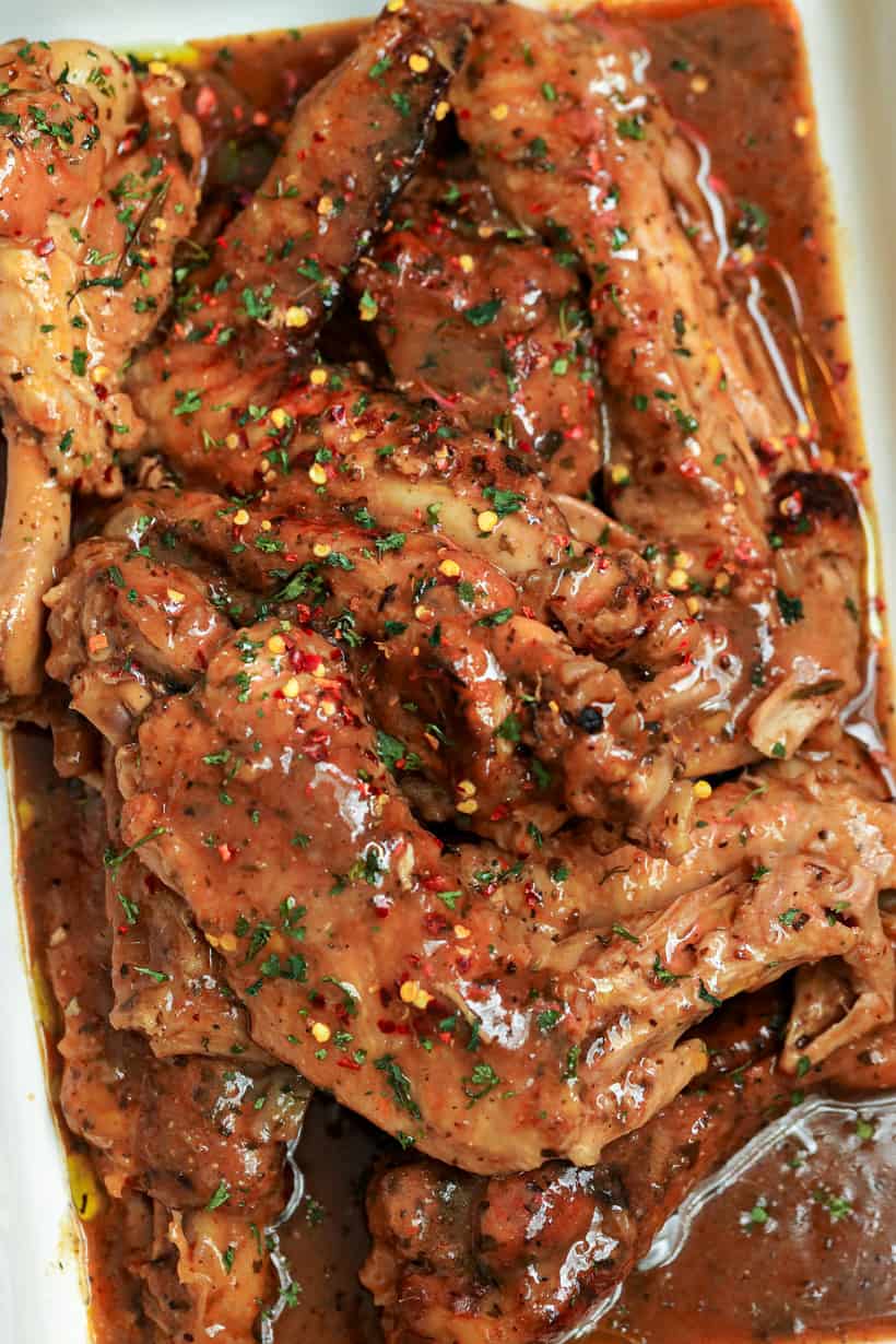 Smothered turkey wings in baking dish topped with red pepper flakes and dried parsley over a bed of rice