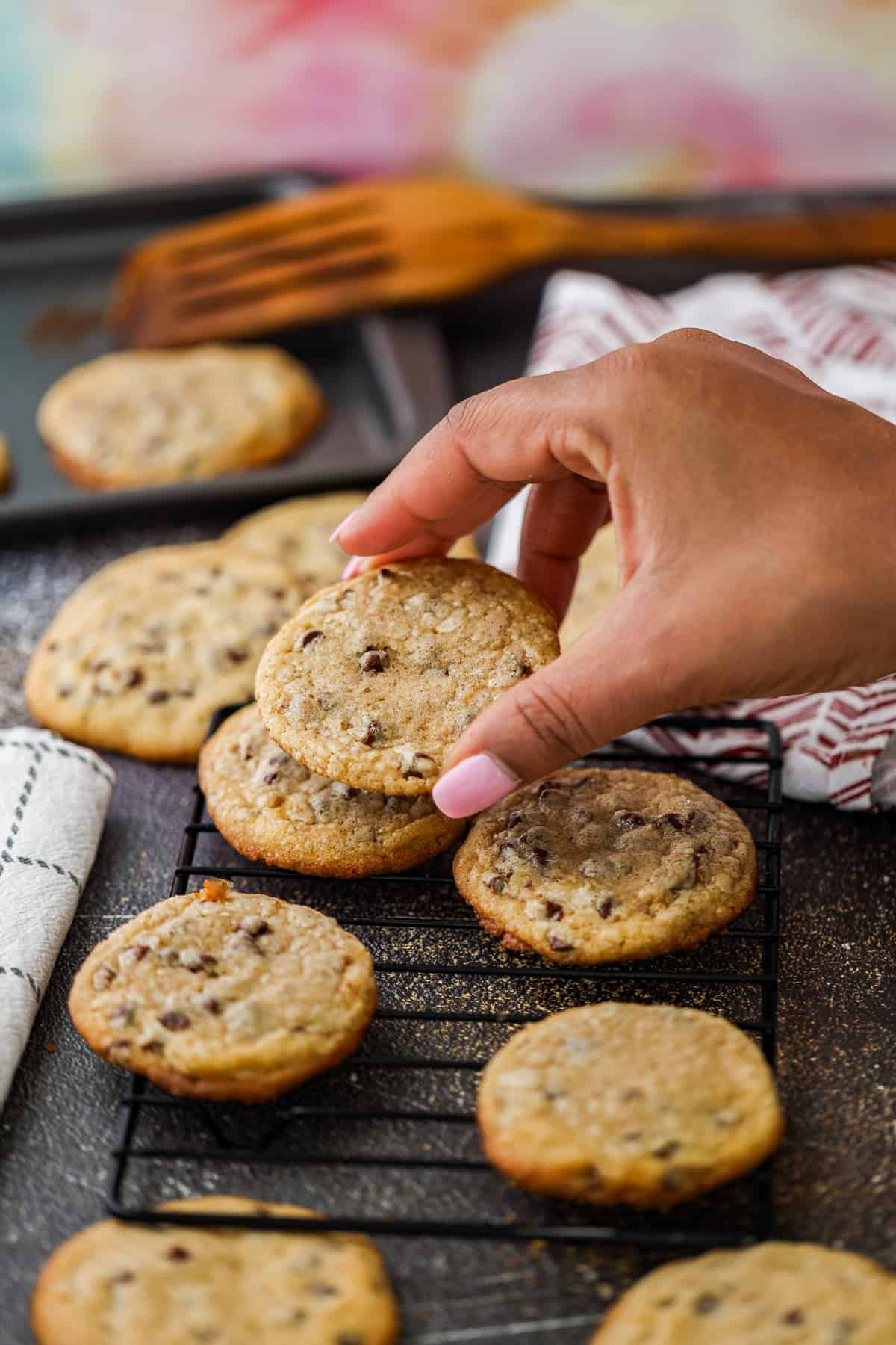 Browned Butter chocolate chip cookies on rack and hand holding cookie