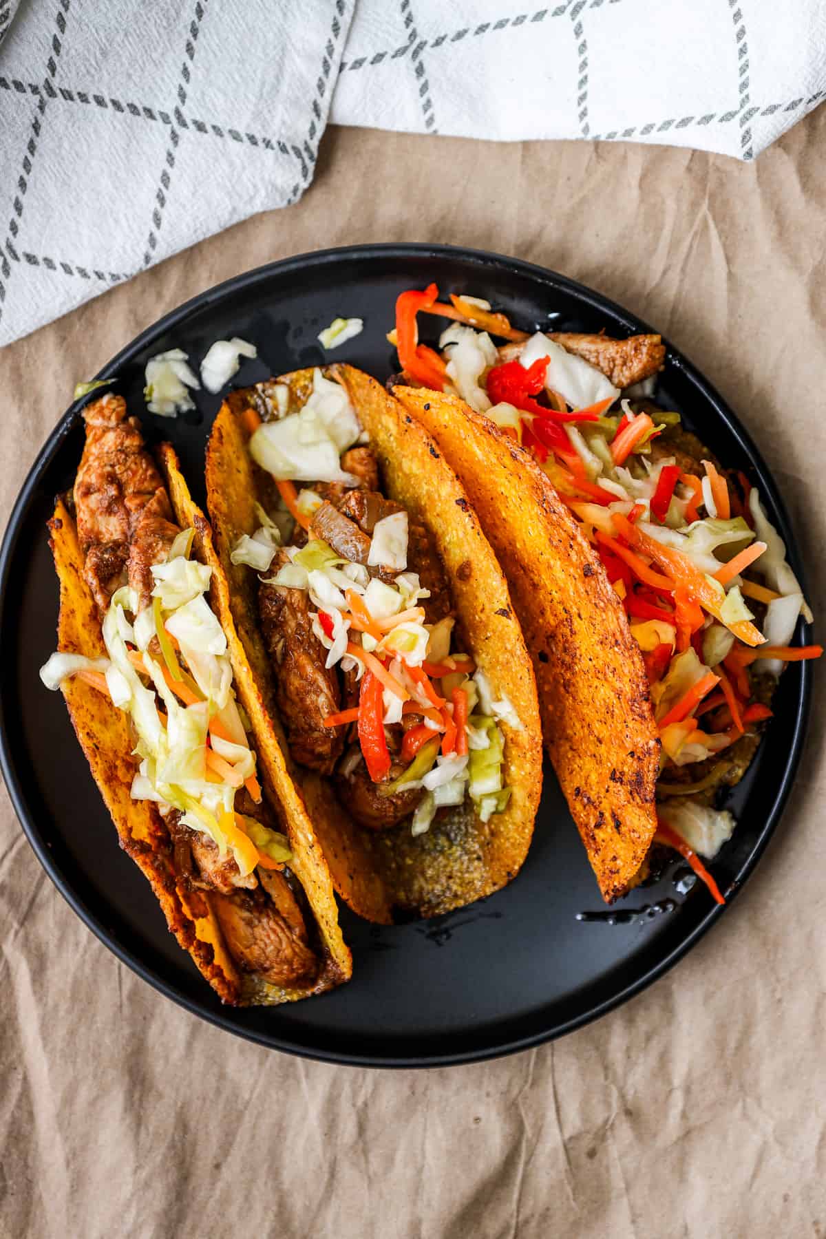 3 tacos toped with pikliz on black plate