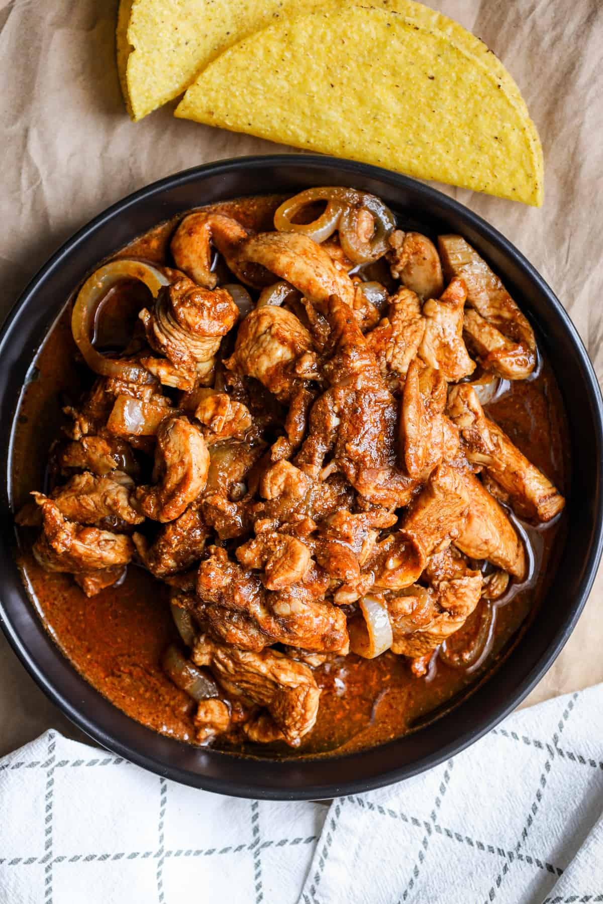 Haitian Style chicken in sauce with two taco shells on the side.