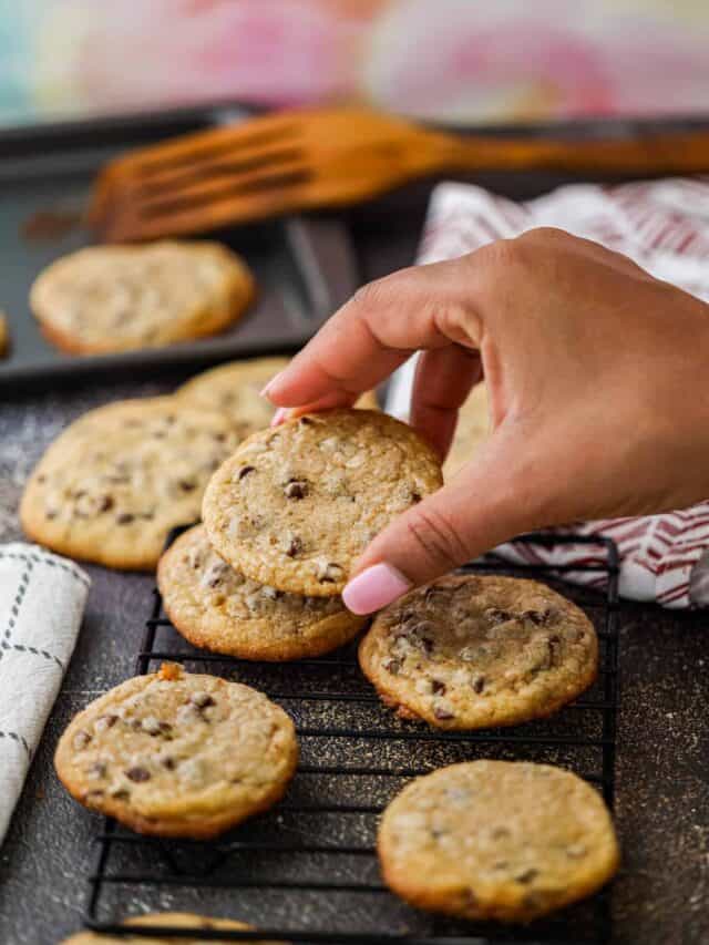 Browned Butter chocolate chip cookies on rack and hand holding cookie