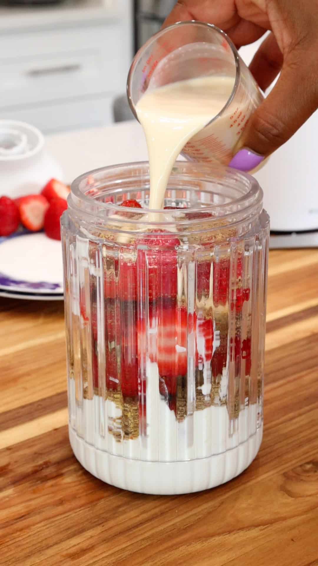 adding milk to strawberries, yogurt, flaxseed in blender