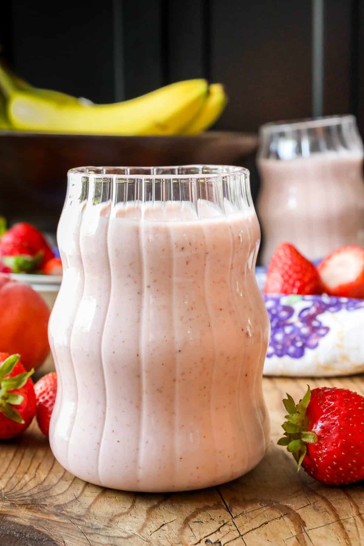 Glass filled with breakfast smoothie prepared with fresh strawberries and bananas.