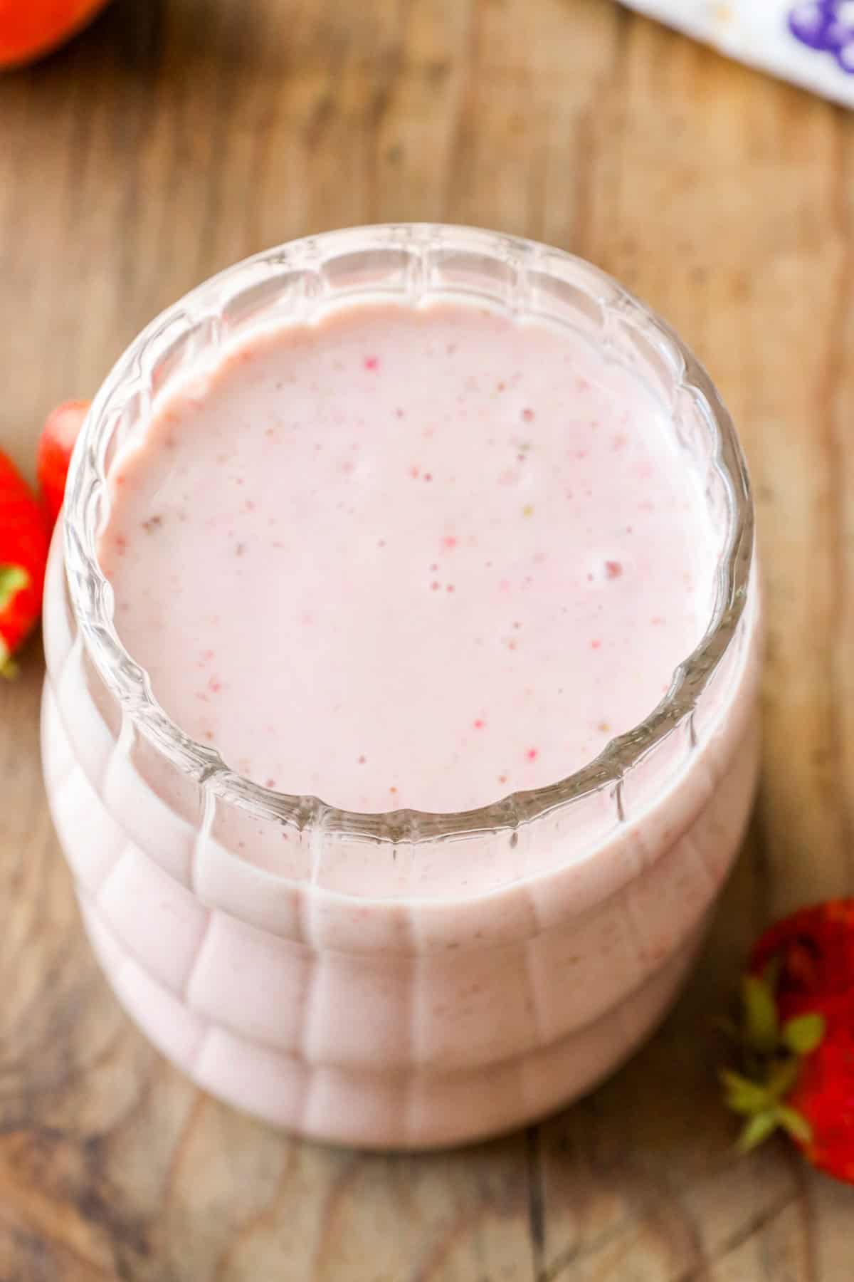 Glass filled with breakfast smoothie prepared with fresh strawberries and bananas.