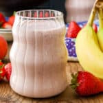 glass filled with breakfast smoothie prepared with fresh strawberries and bananas.