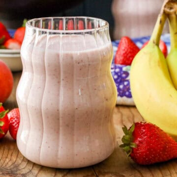 glass filled with breakfast smoothie prepared with fresh strawberries and bananas.