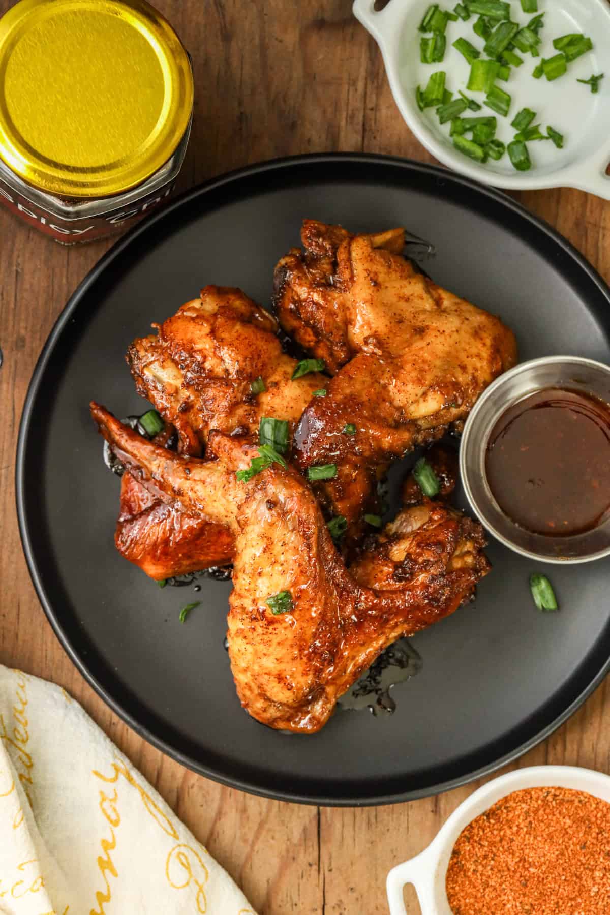 Chipotle Chicken Wings on black plate with chives and seasoning on white plate