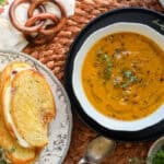 Pumpkin Carrot soup in white bowl with grilled cheese on the side