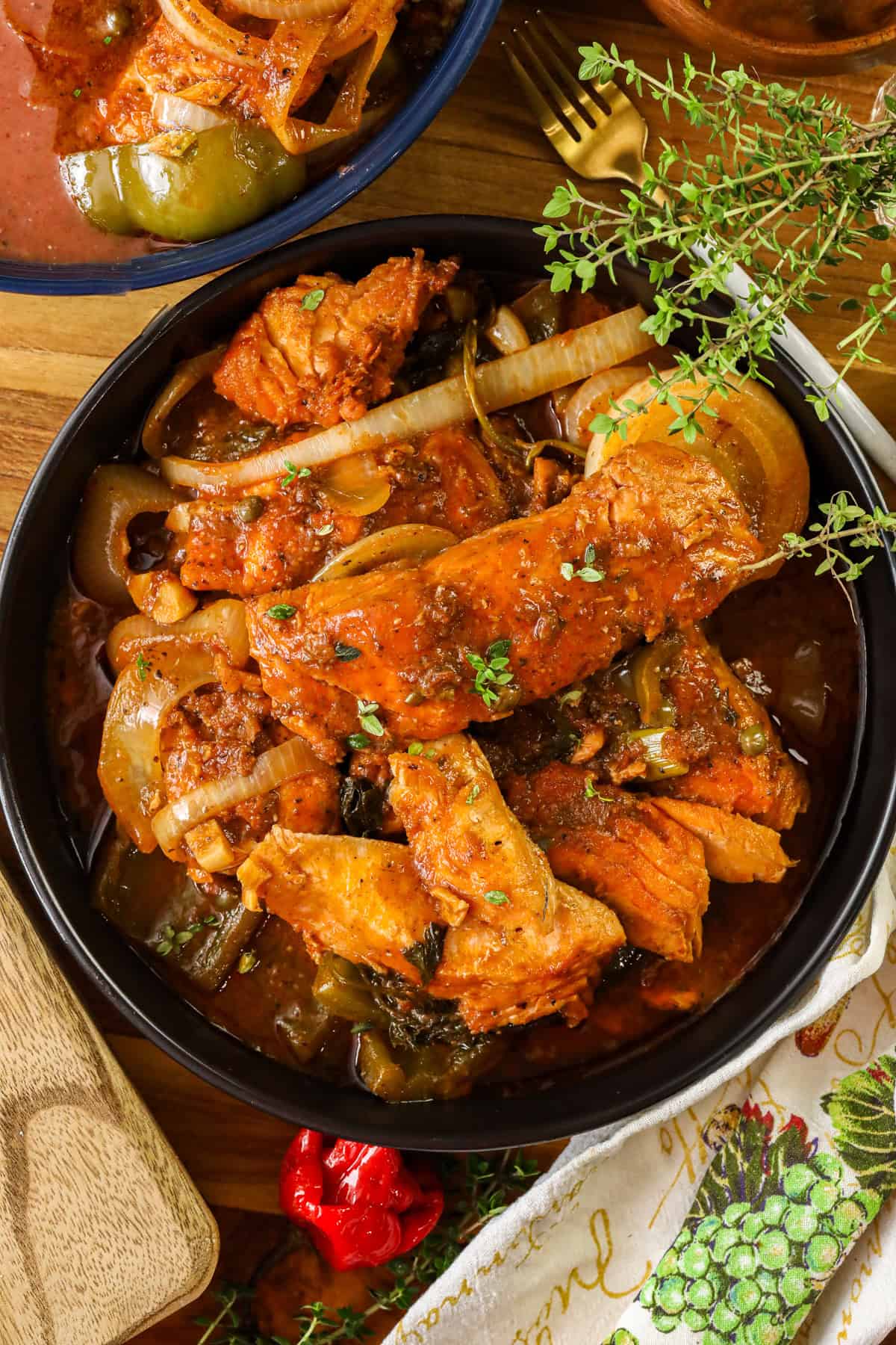 Haitian salmon stew in black bowl mixed with bell peppers and onions.