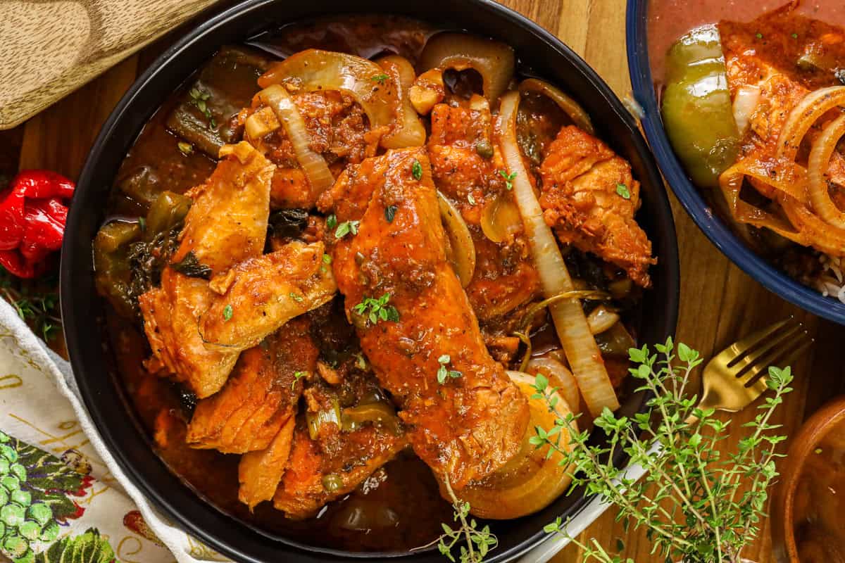 Haitian salmon stew in saucepan mixed with bell peppers and onions.