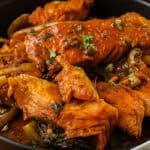 Haitian salmon stew in black bowl mixed with bell peppers and onions.