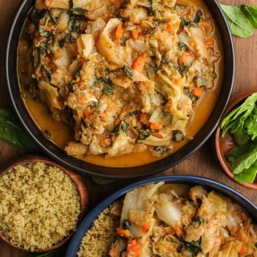 Haitian legume in black bowl, with quinoa and spinach on the side on a wooden board.