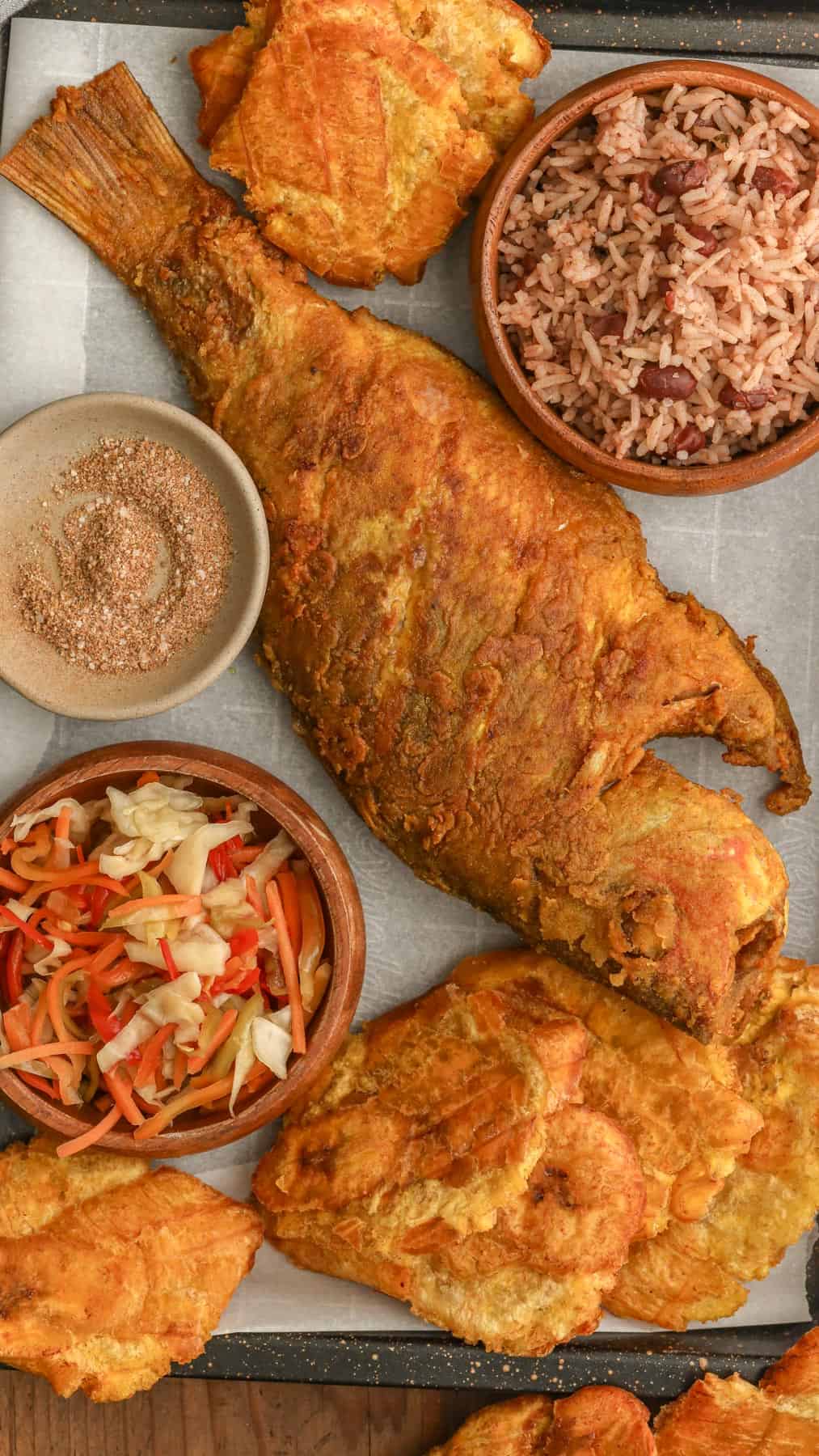 Fried Red Snapper in a tray with Haitian red beans and rice, pikliz, and Jacmel seasoning.