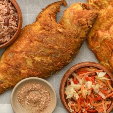 Fried Red Snapper in a tray with Haitian red beans and rice, pikliz, and Jacmel seasoning.