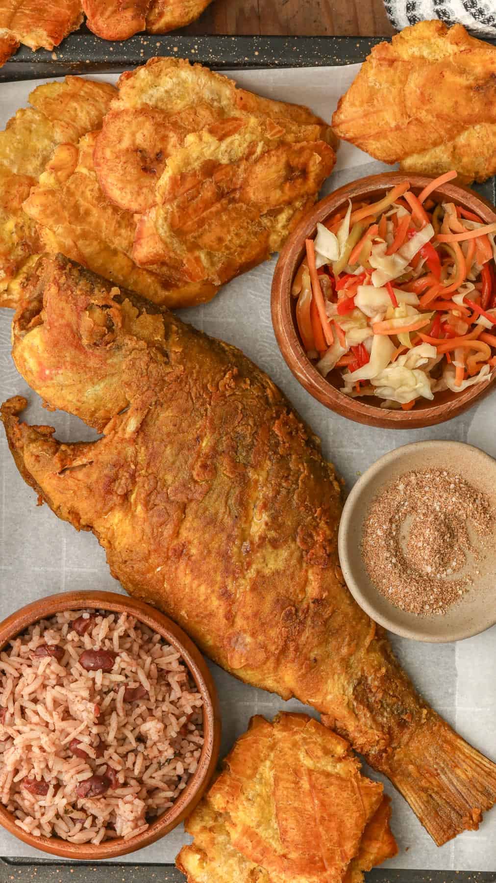 Fried Red Snapper in a tray with Haitian red beans and rice, pikliz, and Jacmel seasoning.