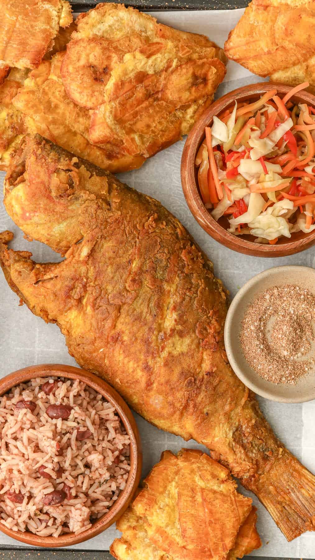 Fried Red Snapper in a tray with Haitian red beans and rice, pikliz, and Jacmel seasoning.