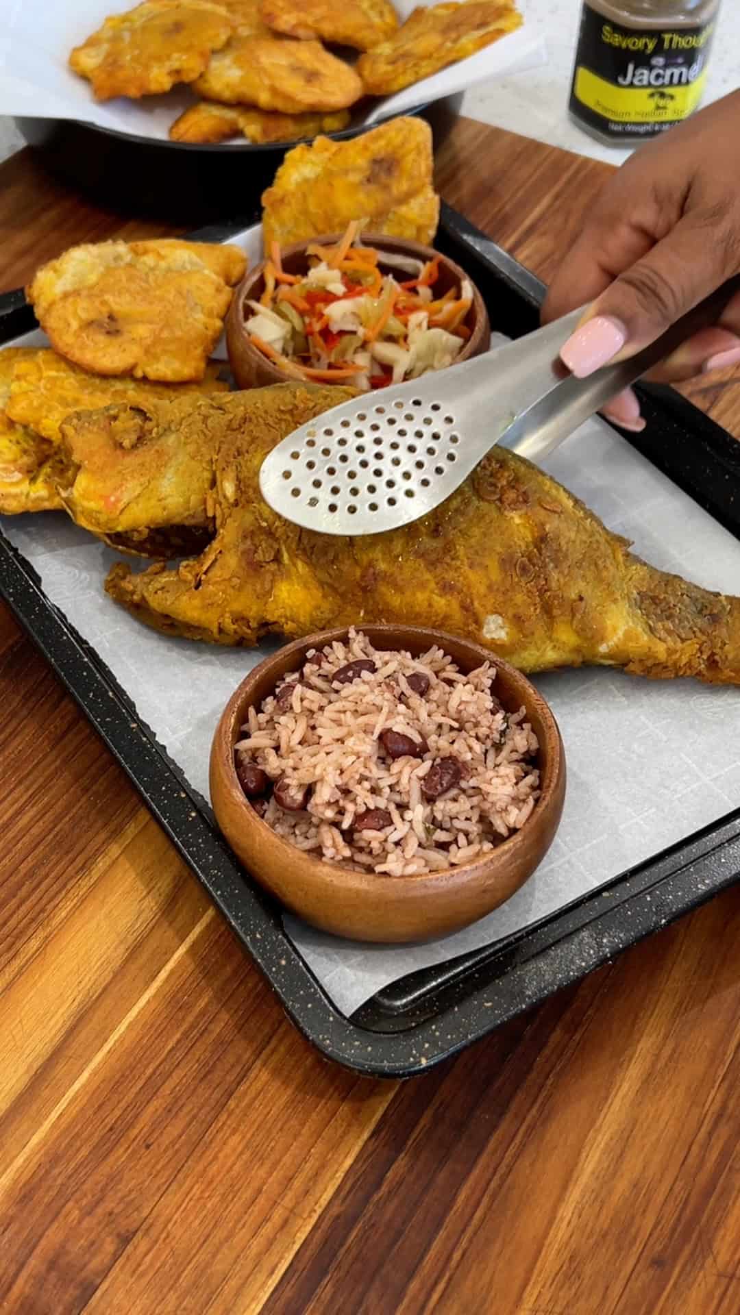 Serving red snapper with red beans and rice, sauce, pikliz and fried plantains