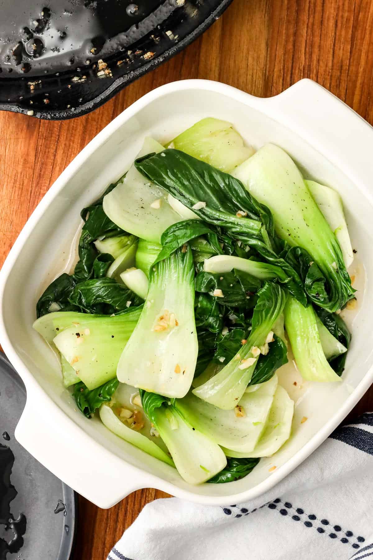 blanched Bok Choy with sautéed garlic in white bowl.