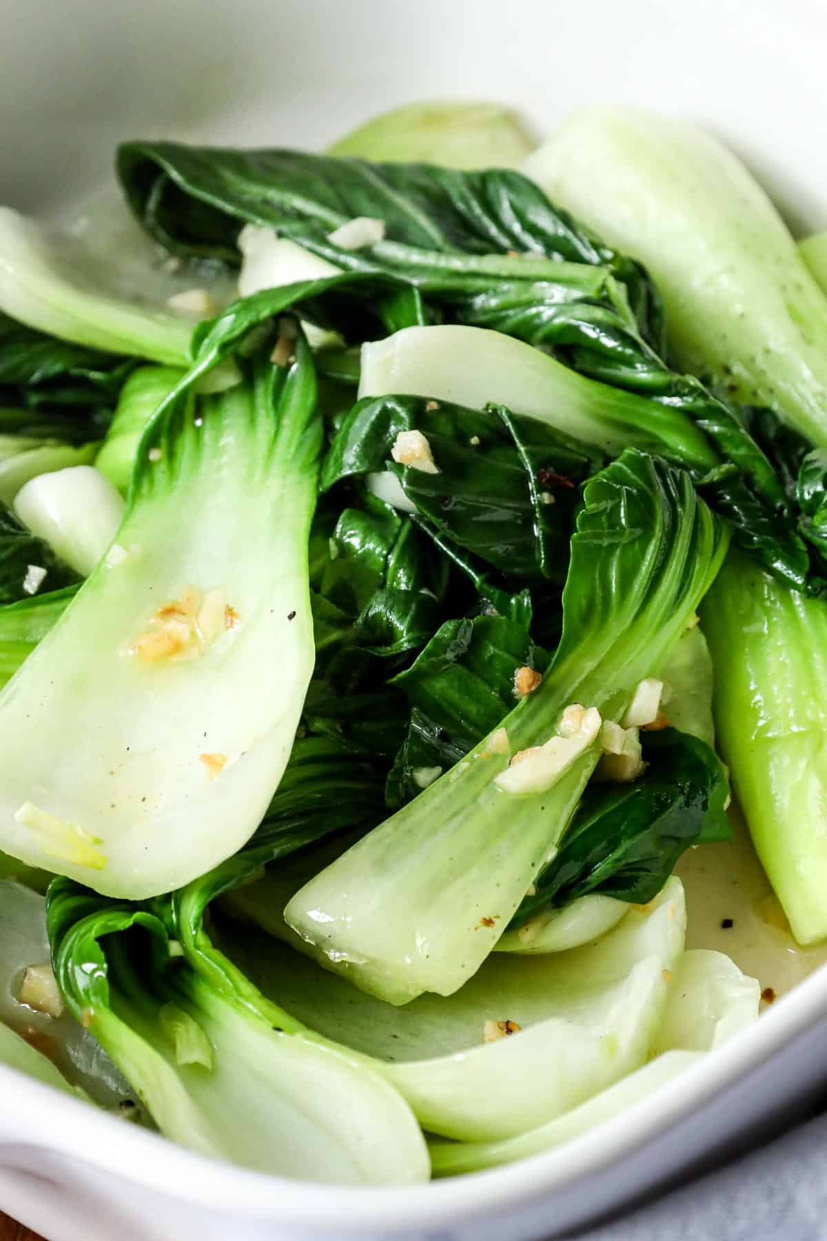 blanched Bok Choy with sautéed garlic in white bowl.