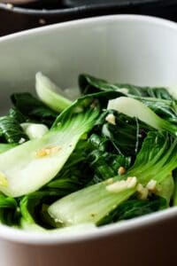 blanched Bok Choy with sautéed garlic in white bowl.