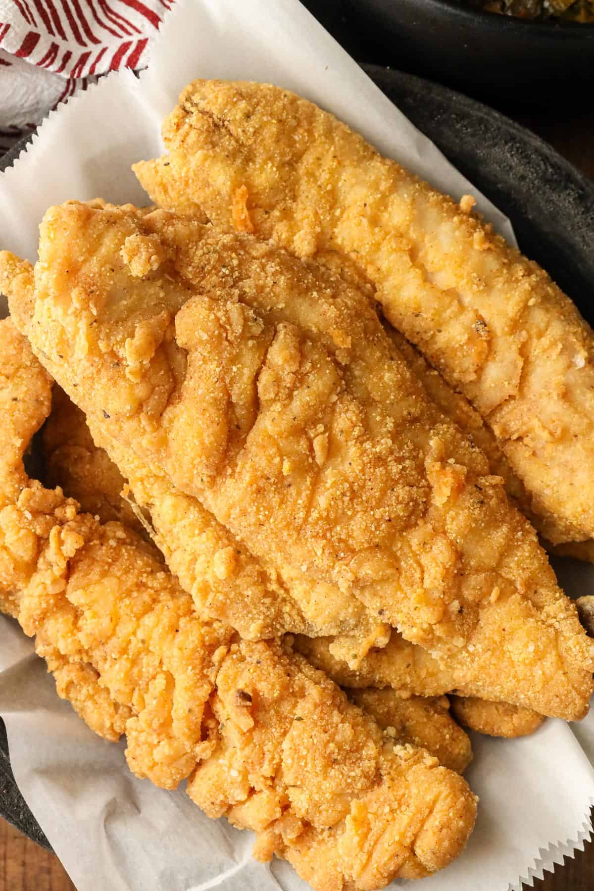 Whiting fish stacked on parchment paper in a bowl.