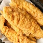 Whiting fish stacked on parchment paper in a bowl.