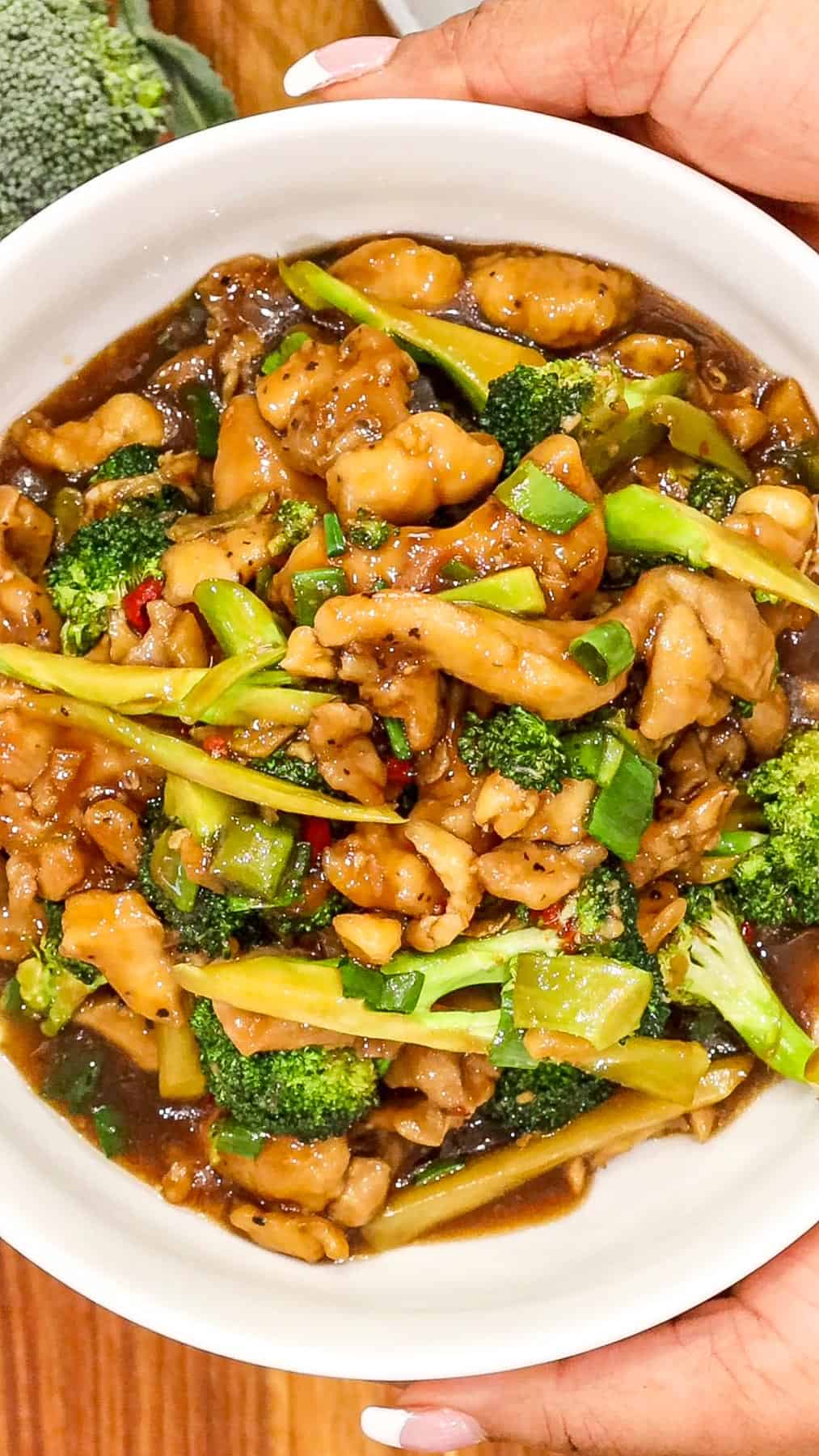 hand holding chicken broccoli stir fry in a bowl