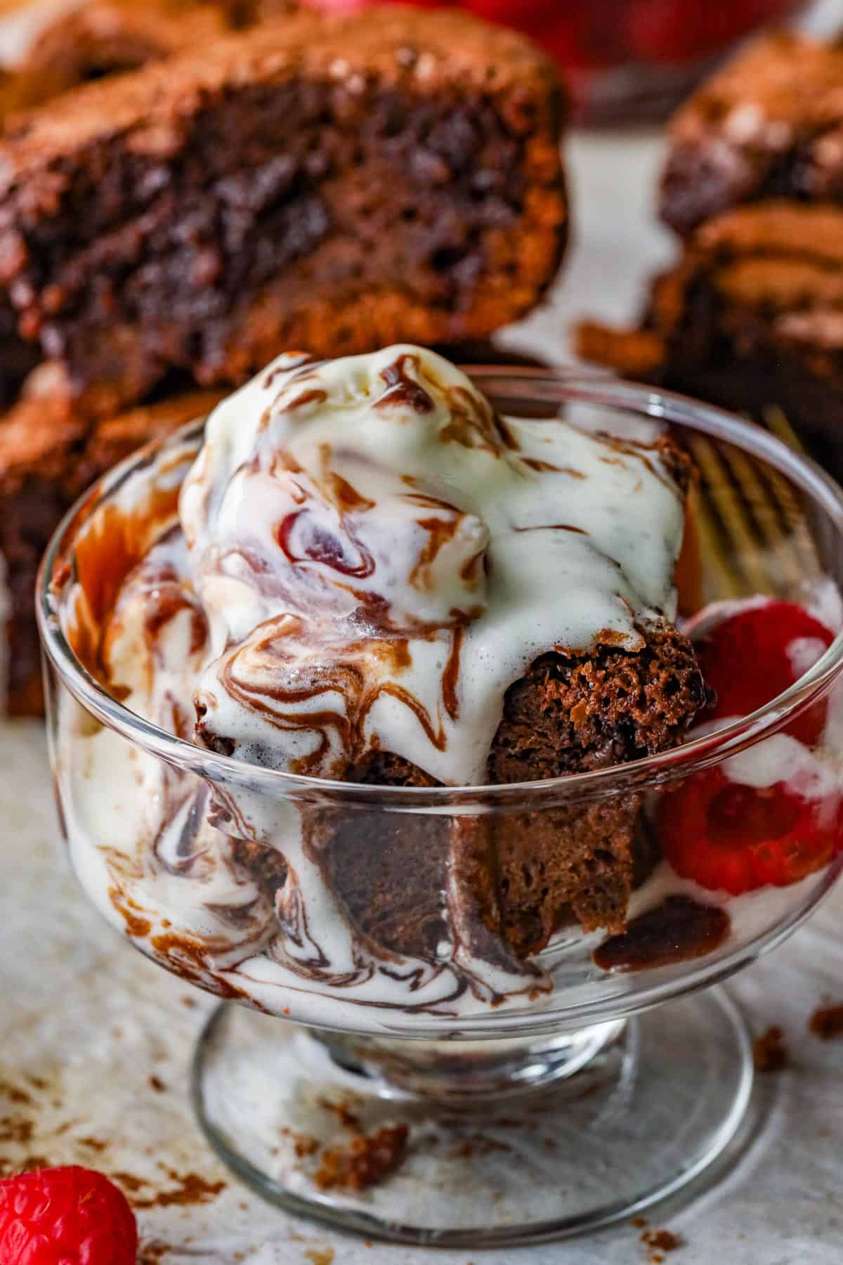 Chocolate Fudge Brownies in glass cup with raspberries on the side.