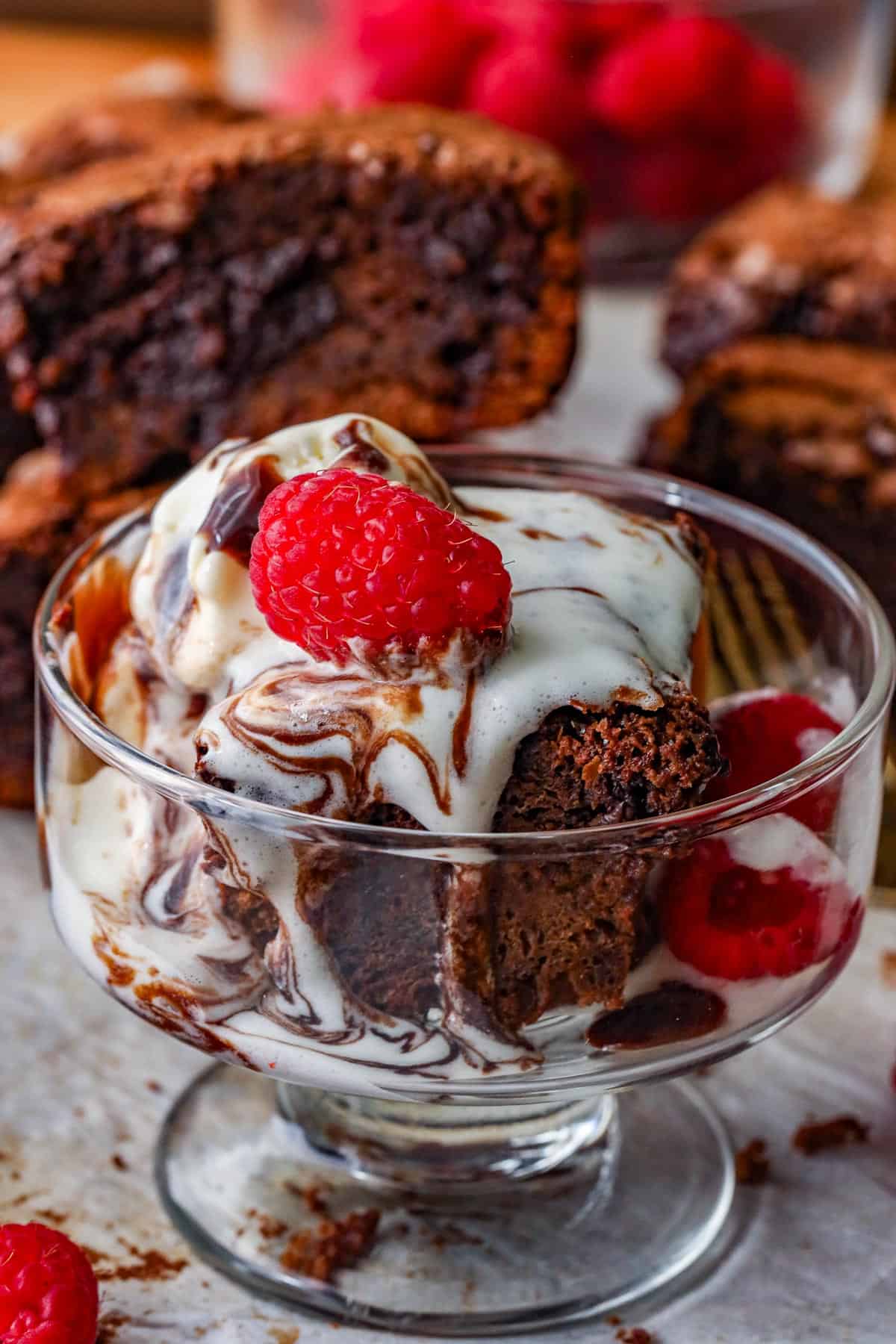 Chocolate Fudge Brownies in glass cup with raspberries on the side and on top.