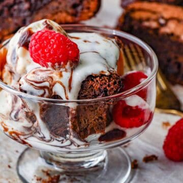 Chocolate Fudge Brownies in glass cup with raspberries on the side and on top.