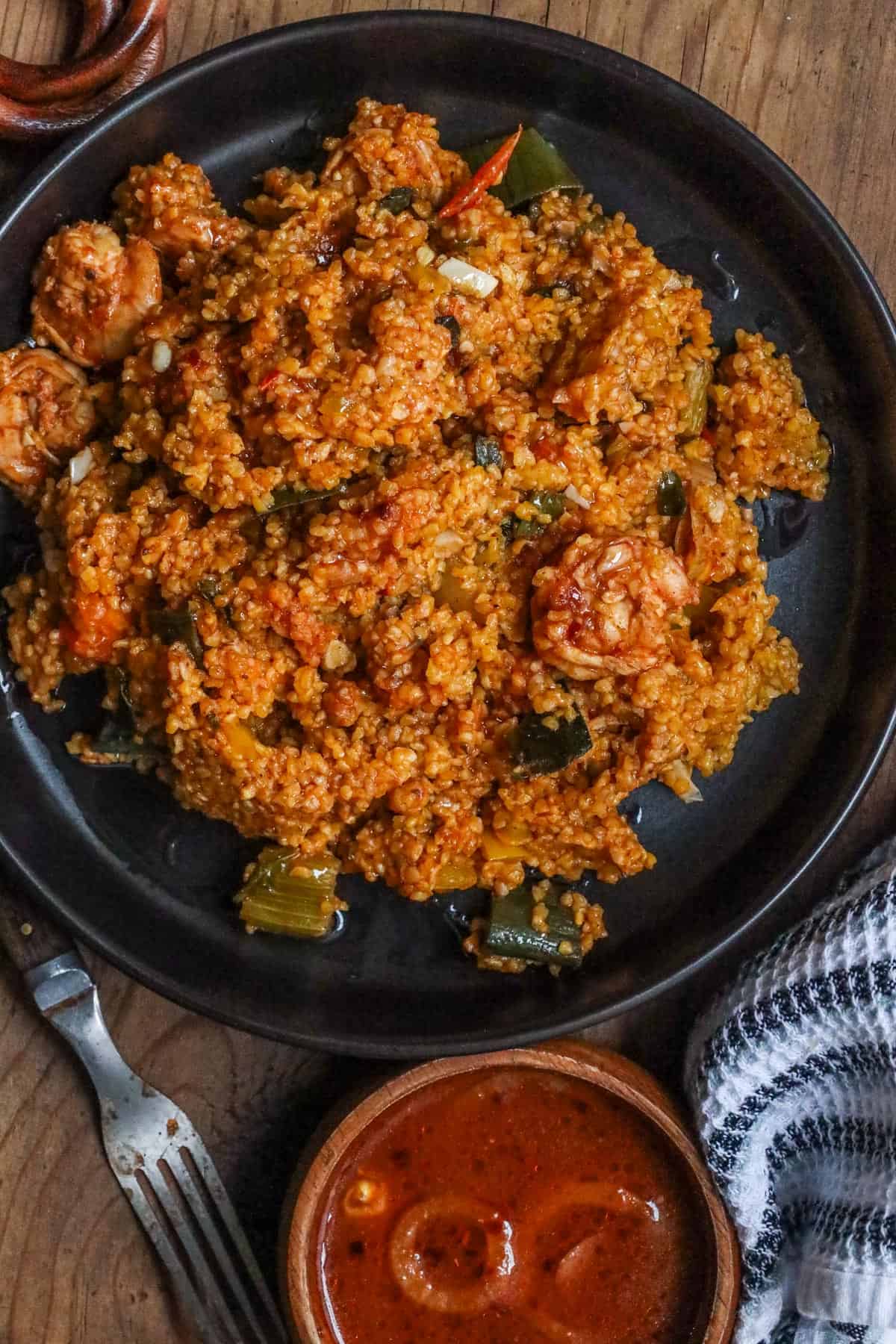 Mayi moulin with shrimp in black bowl with sauce on the side and fork